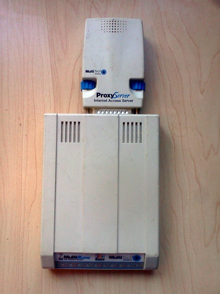 Stacked MultiTech ProxyServer and 56K MultiModem on a wooden surface